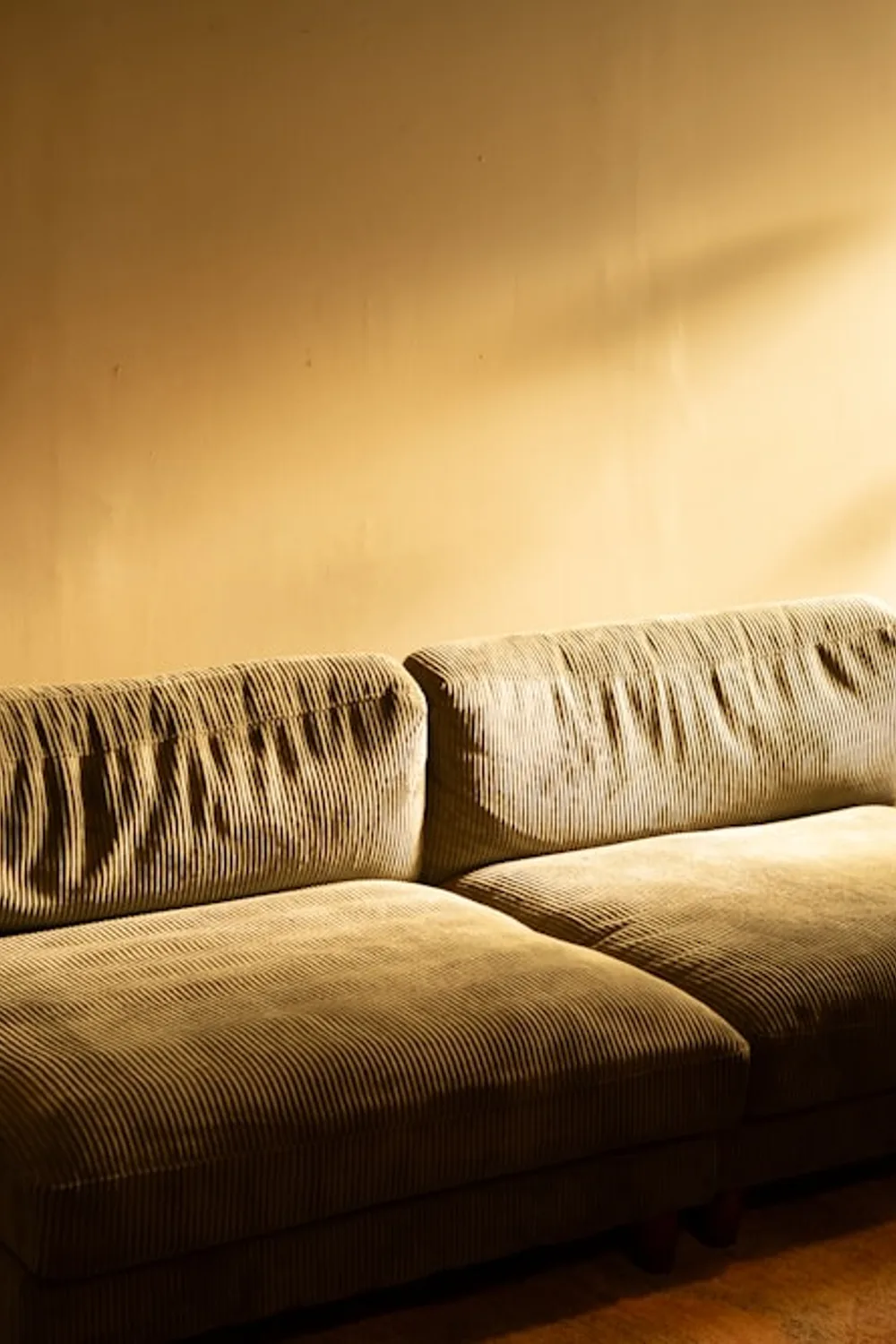 Textured neutral sofa beside a wooden side table and floor lamp in warm golden light.